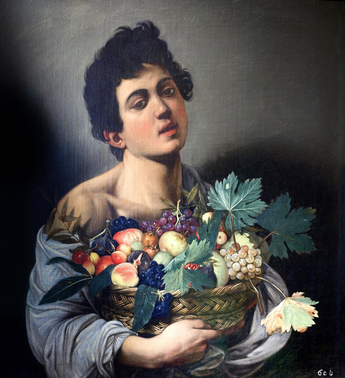 Boy with a Basket of Fruit by Caravaggio: a youth with a bare shoulder holding a basket of grapes, peaches and leaves.