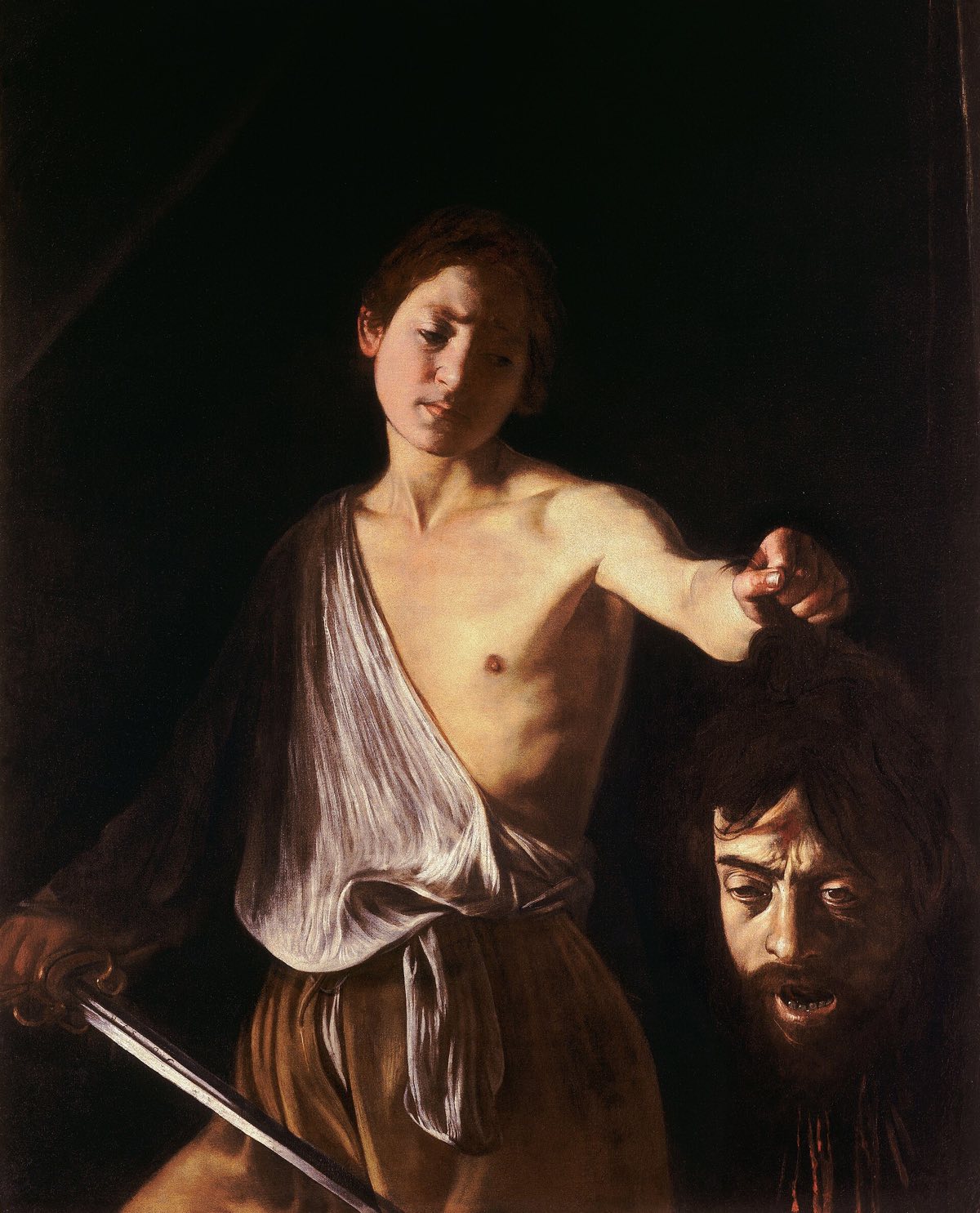 David with the Head of Goliath by Caravaggio: a boy holds out the severed head by its hair, against darkness.