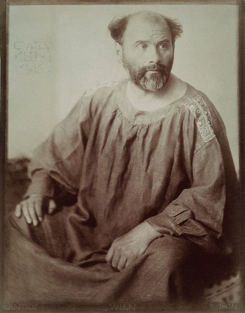 A photograph of Gustav Klimt in his painter's smock, holding a cat.