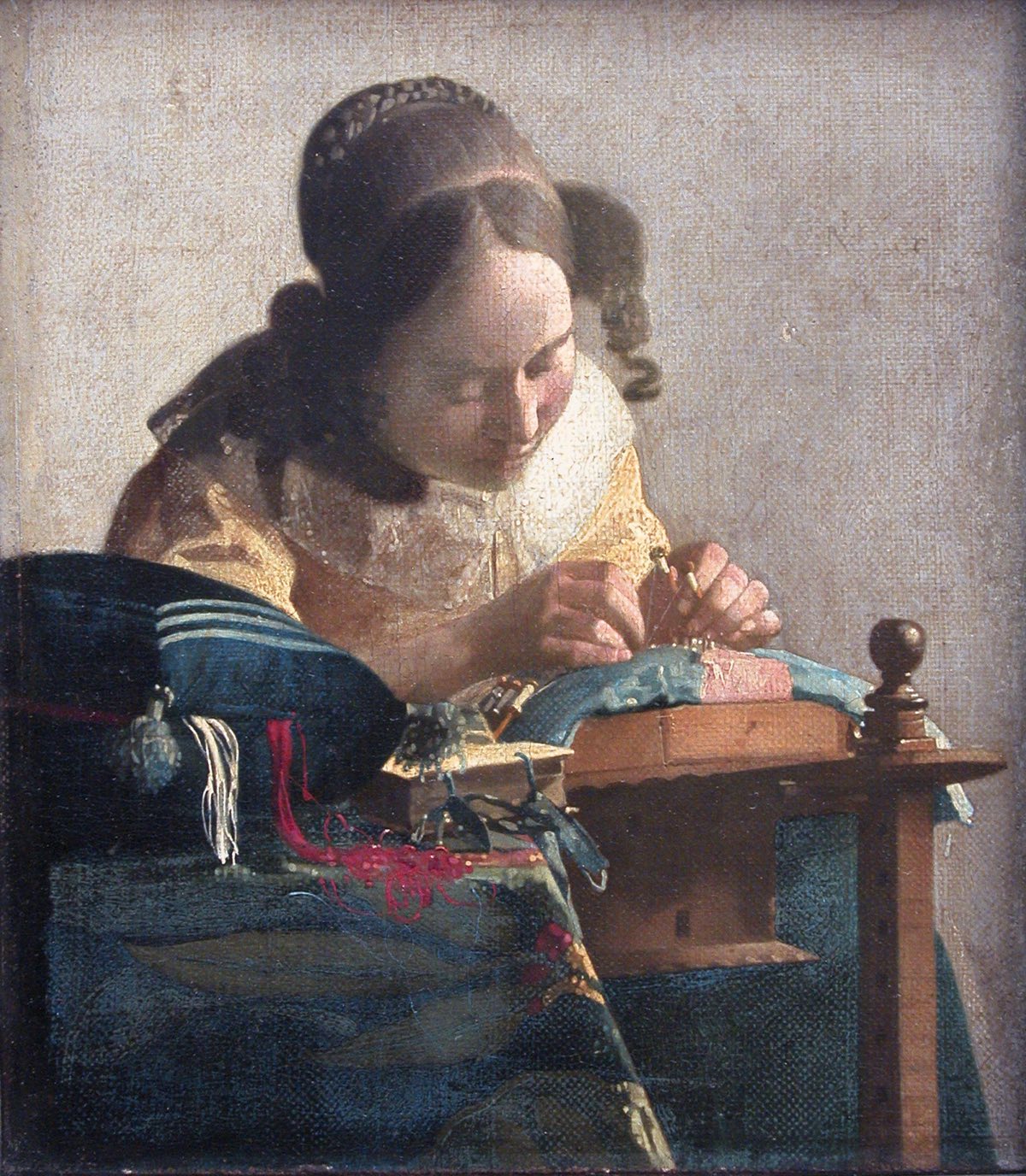 The Lacemaker, by Vermeer: a girl in yellow bent over her lace pillow.