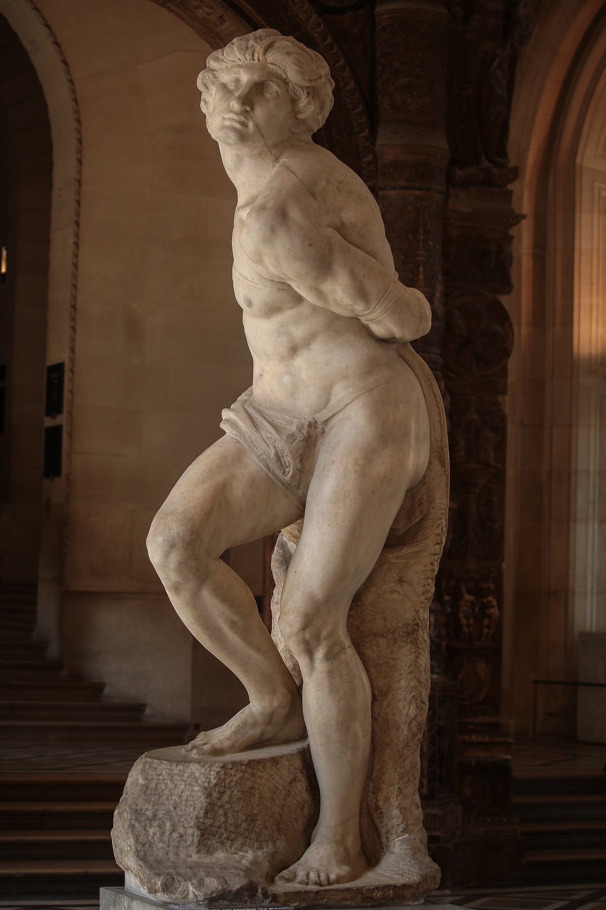 Michelangelo's Rebellious Slave in the Louvre, a marble figure twisting against his bonds.