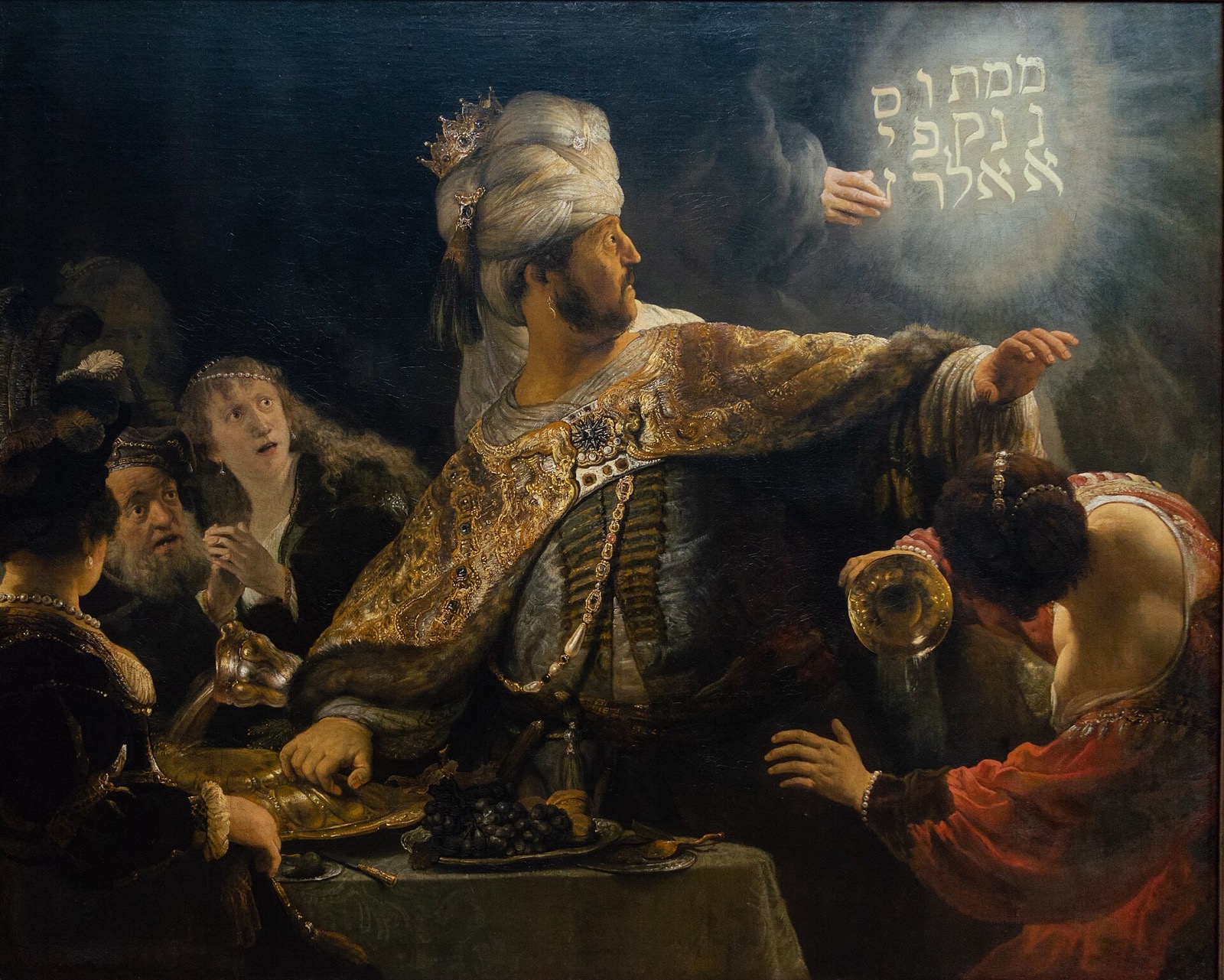 Belshazzar's Feast, by Rembrandt: the king starts up from the table as a hand writes in light on the wall.