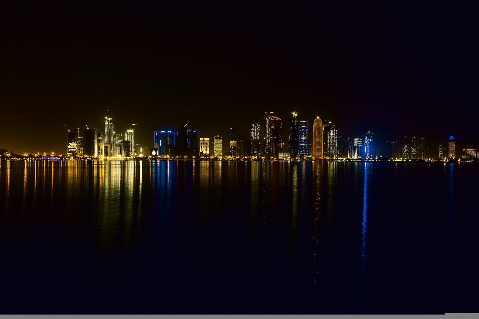 The skyline of Doha at night, reflected in the bay.