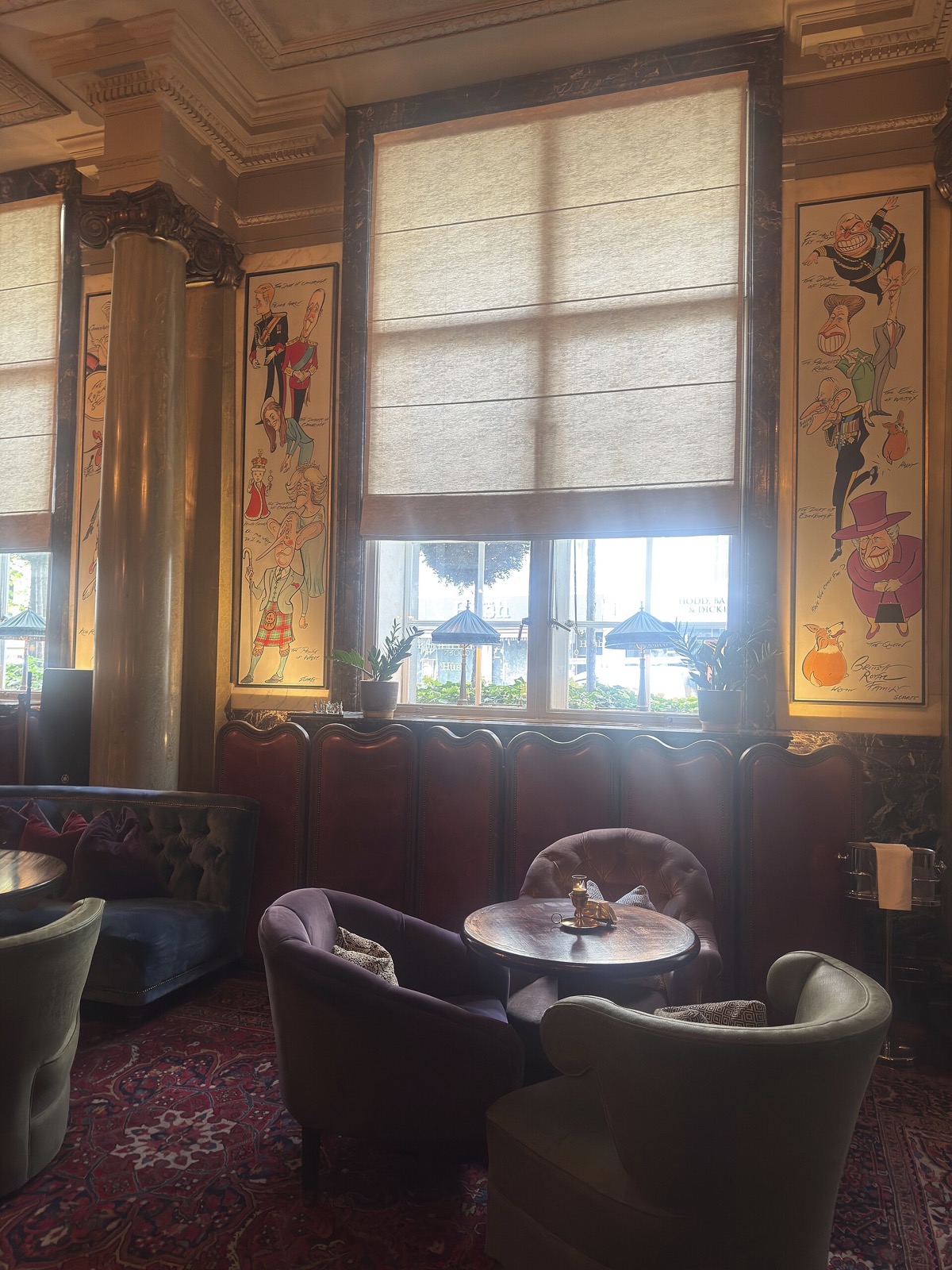 A corner of Scarfes Bar at the Rosewood London, with leather chairs under a tall window.