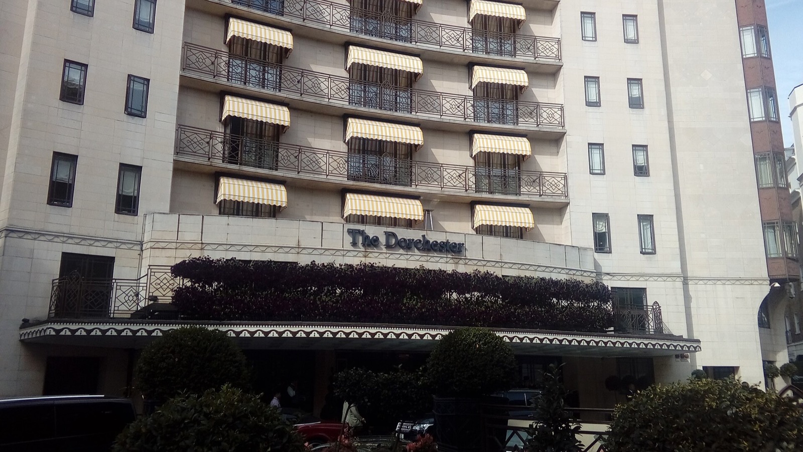 The front of the Dorchester, rows of balconies with striped awnings.