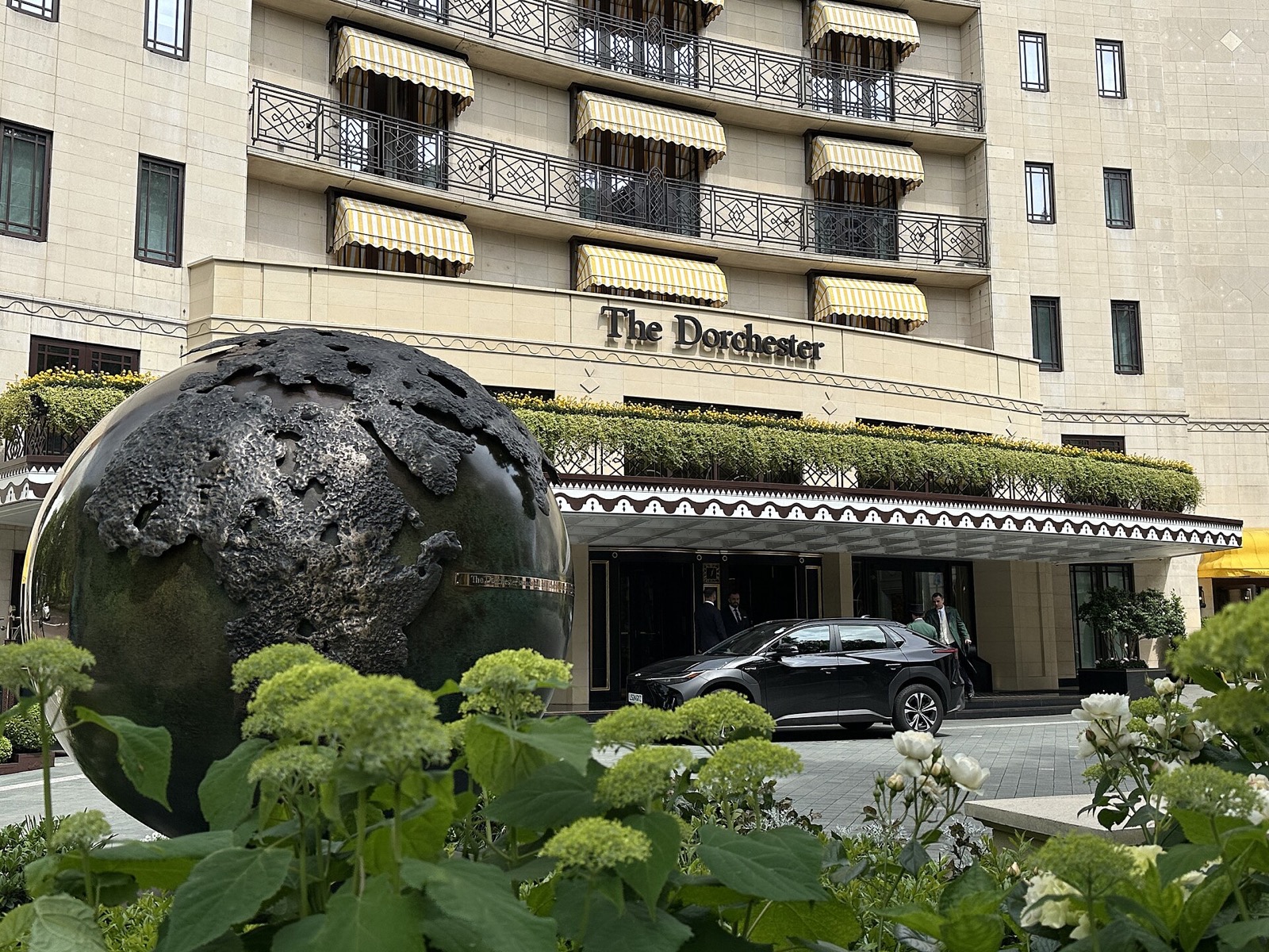 The Dorchester on Park Lane, its curved front of balconies behind a plane tree and a fountain.