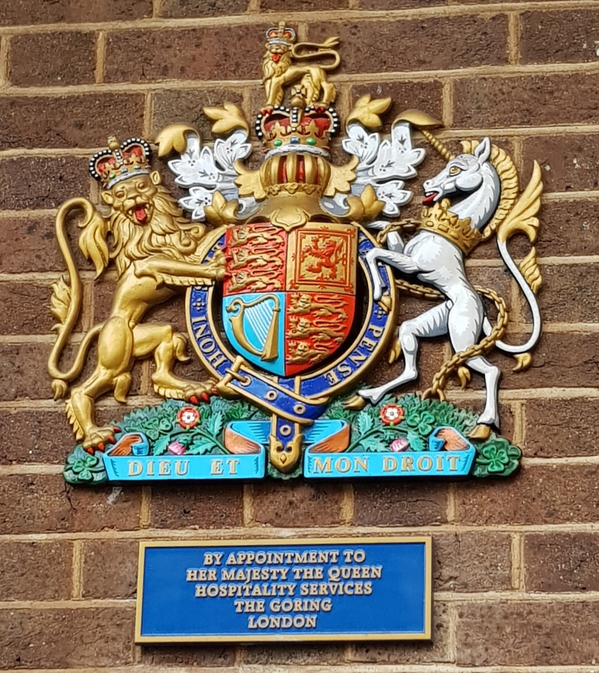 The royal arms on the wall of the Goring, with the plaque of its royal warrant.