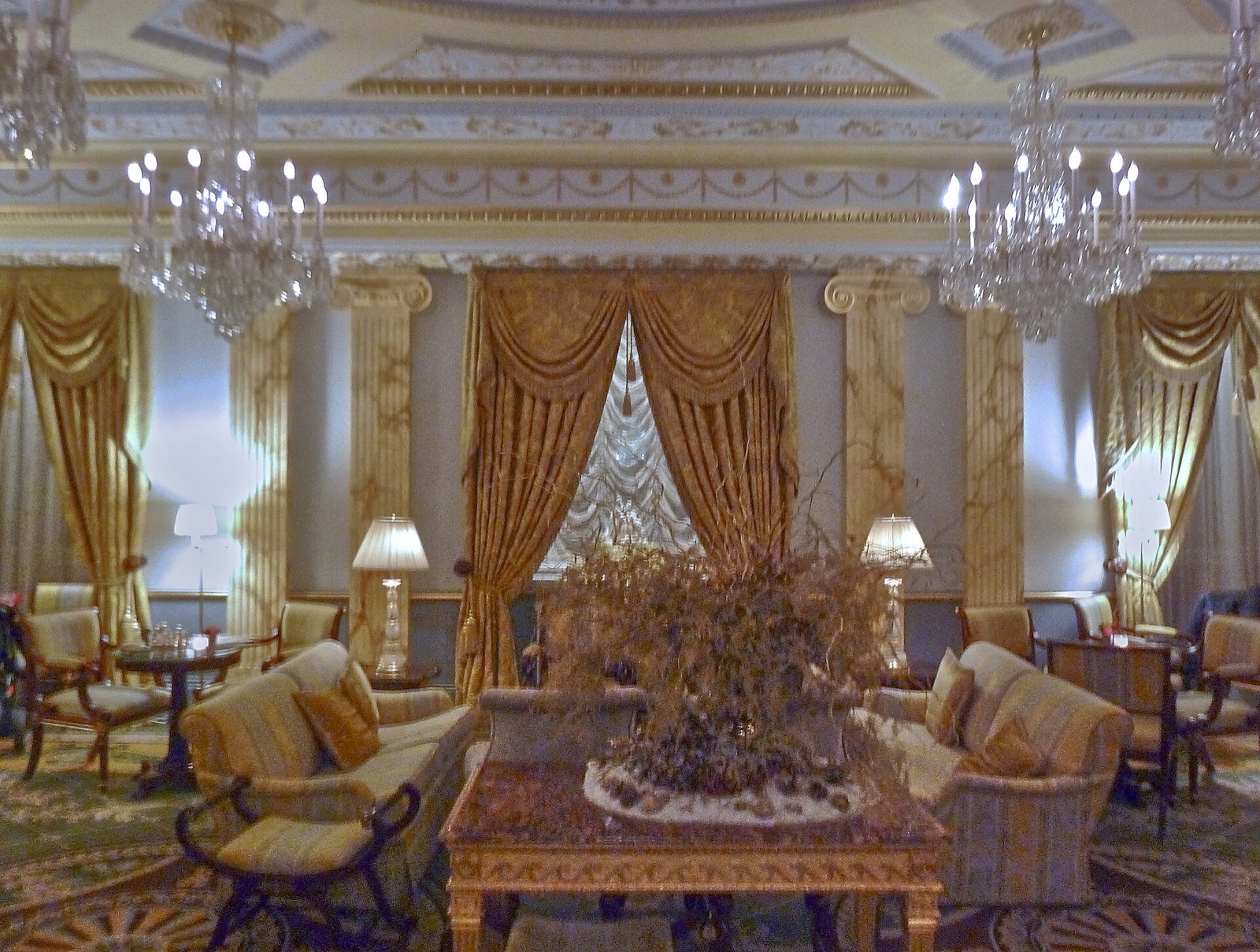 A drawing room of the Lanesborough, with gilded mirrors, swagged curtains and chandeliers.