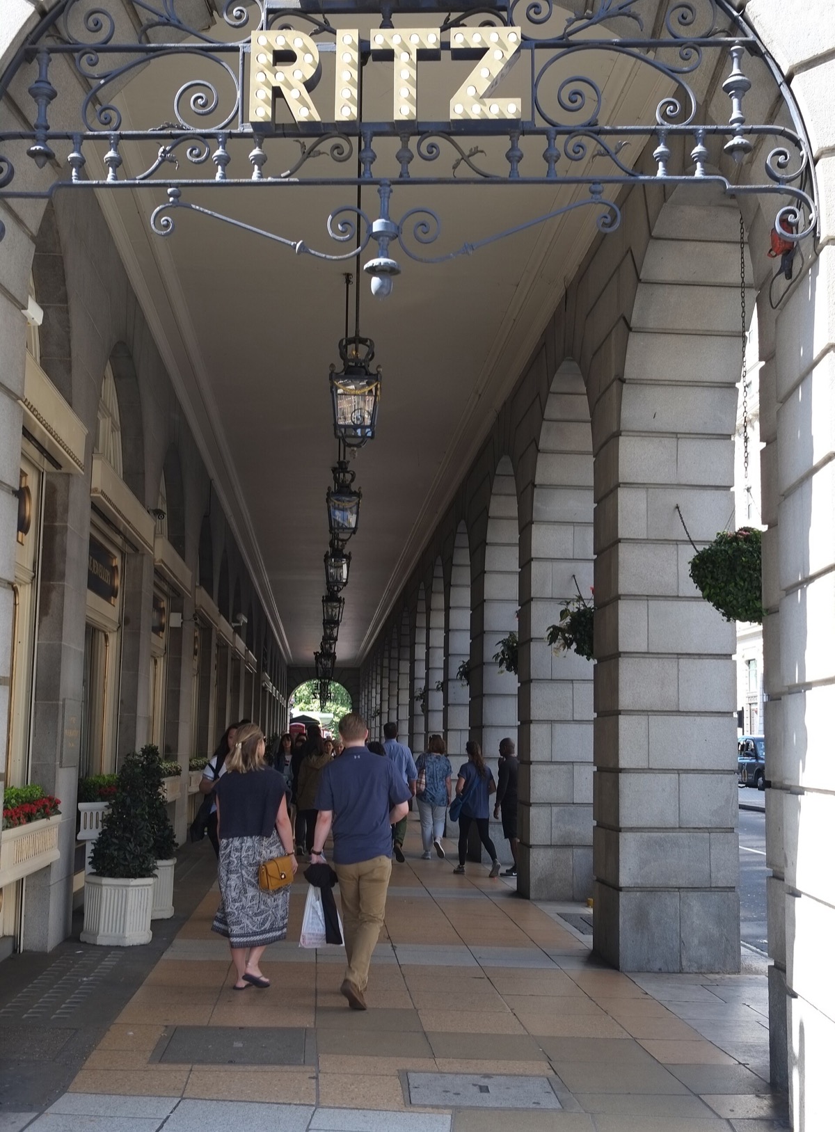 The arcade of the Ritz on Piccadilly, with the hotel's name on a hanging sign.