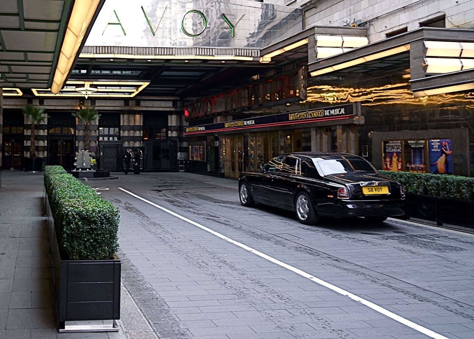 A car drawing up in Savoy Court, the short street to the door of the Savoy, under the hotel's steel sign.