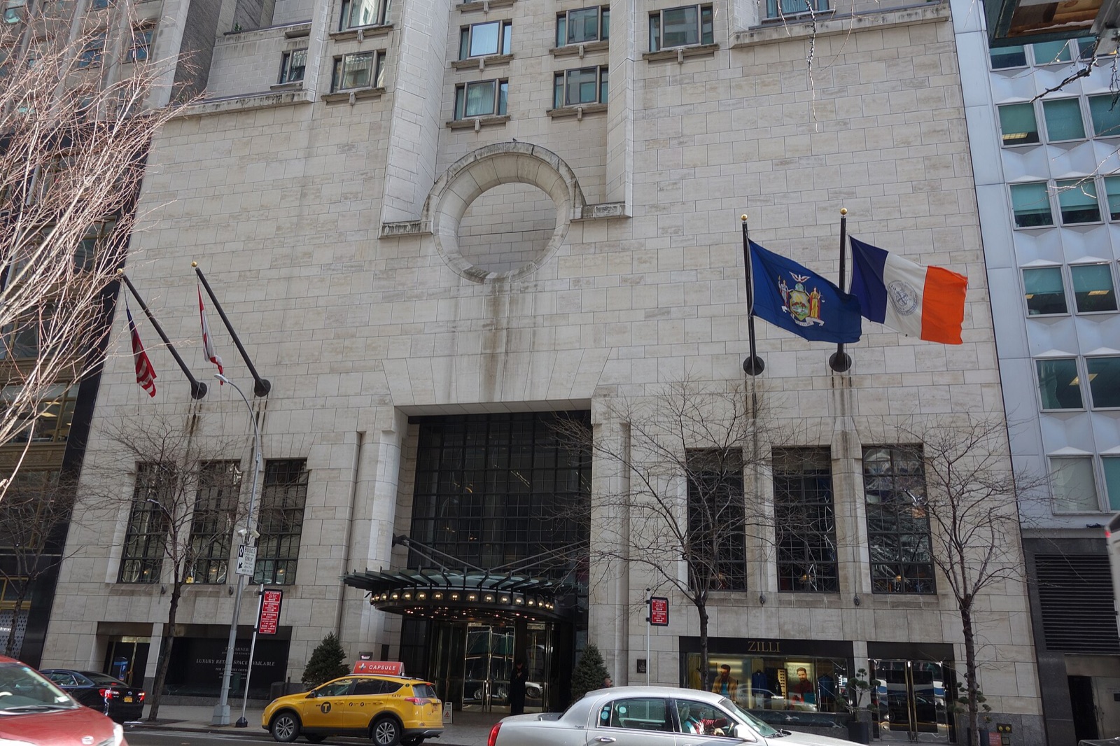 The base of the Four Seasons Hotel New York on 57th Street, in pale limestone with flags over the door.
