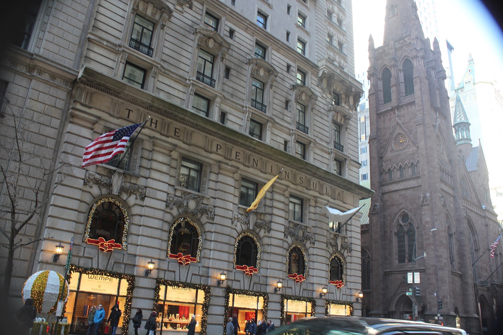 The Peninsula New York on Fifth Avenue at 55th Street, with a church spire beyond it.