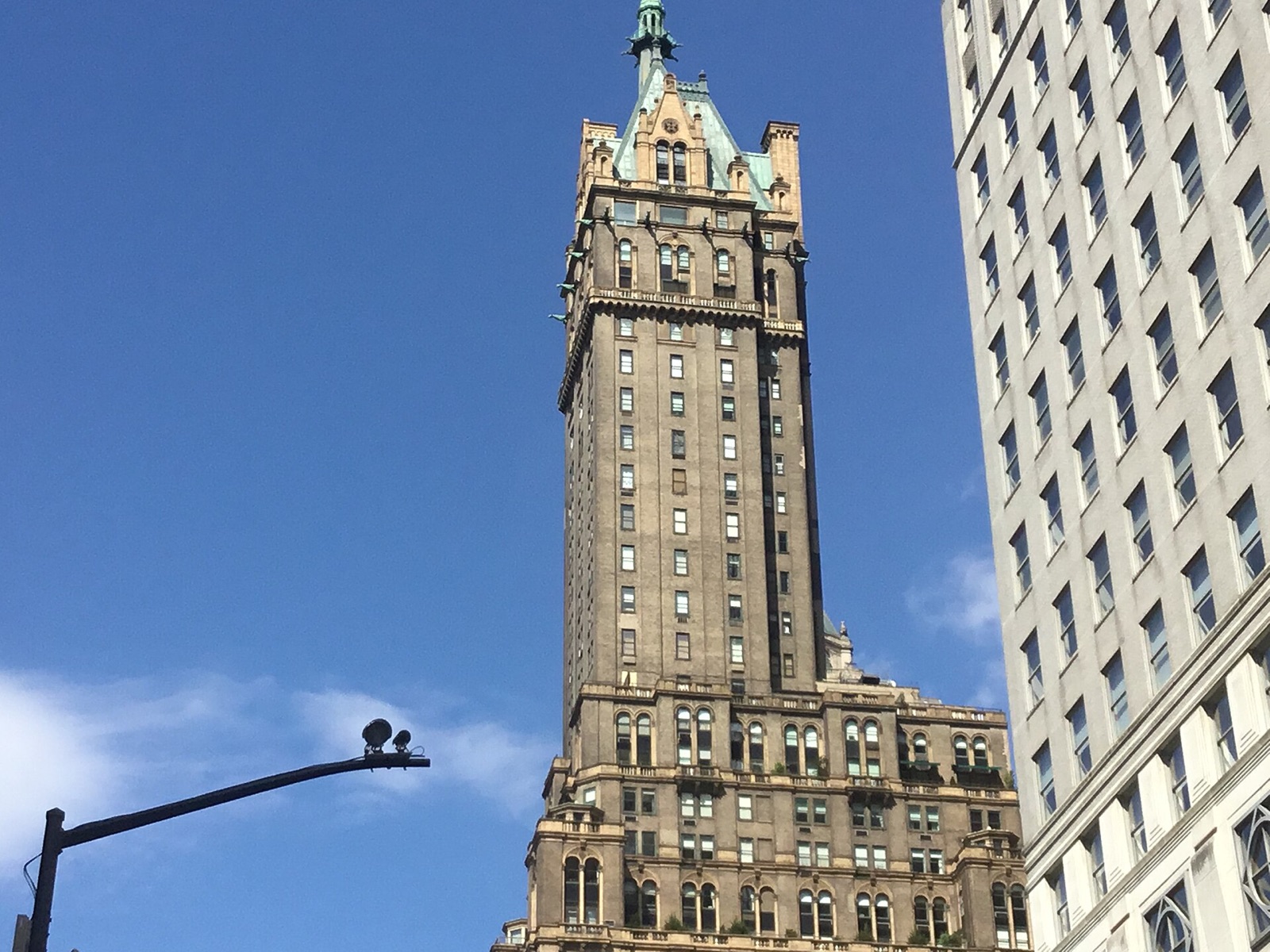 The top of the Sherry-Netherland, a brick tower ending in a Gothic spire, beside a glass office block.