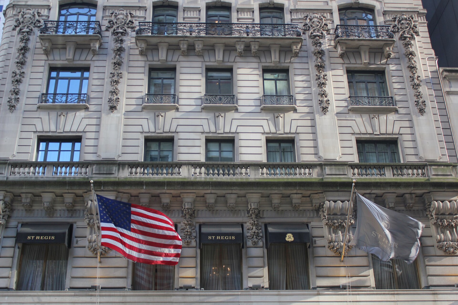 The St. Regis New York on Fifth Avenue, its limestone front carved with balconies under a mansard roof.