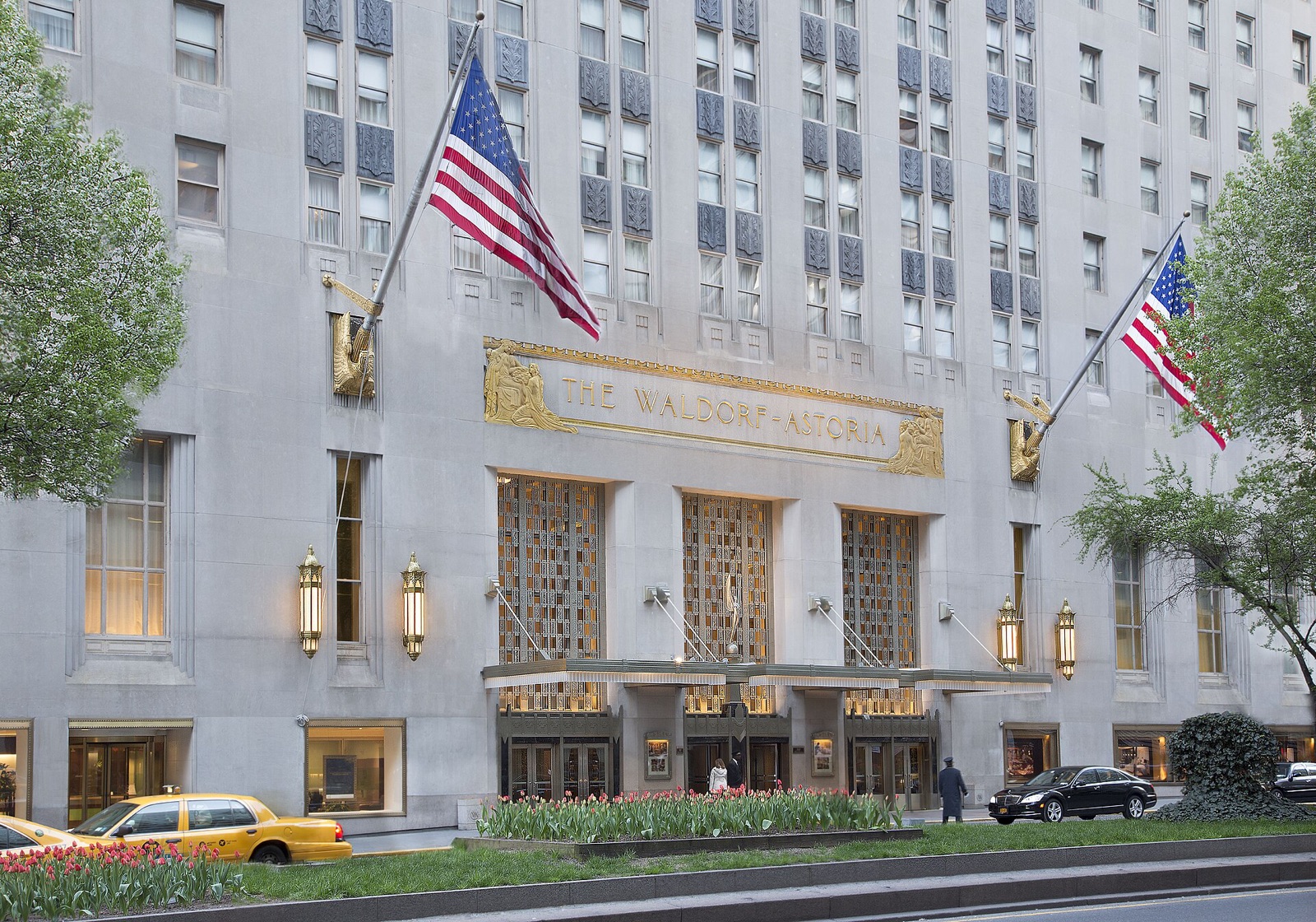 The Park Avenue entrance of the Waldorf Astoria, with flags over a gilded canopy.