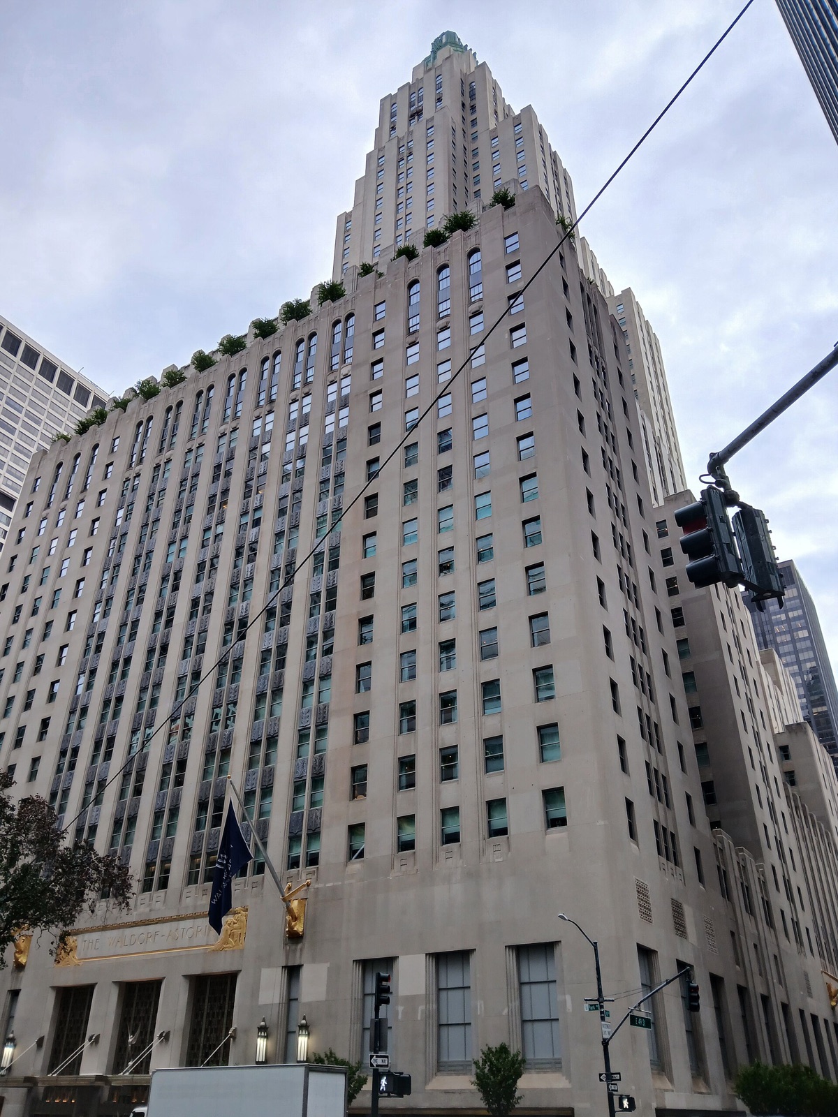 The Waldorf Astoria from Park Avenue, a stepped limestone block ending in two towers.