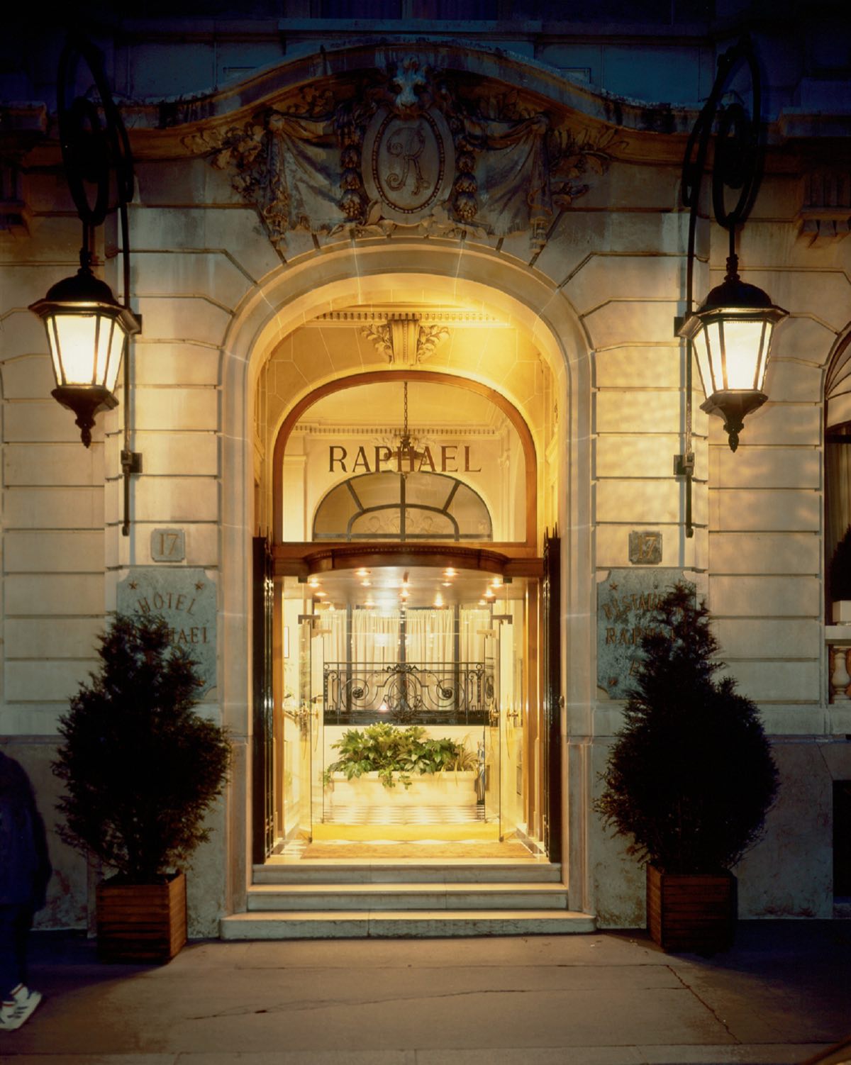 The entrance of the Hôtel Raphael at night, lit from inside.