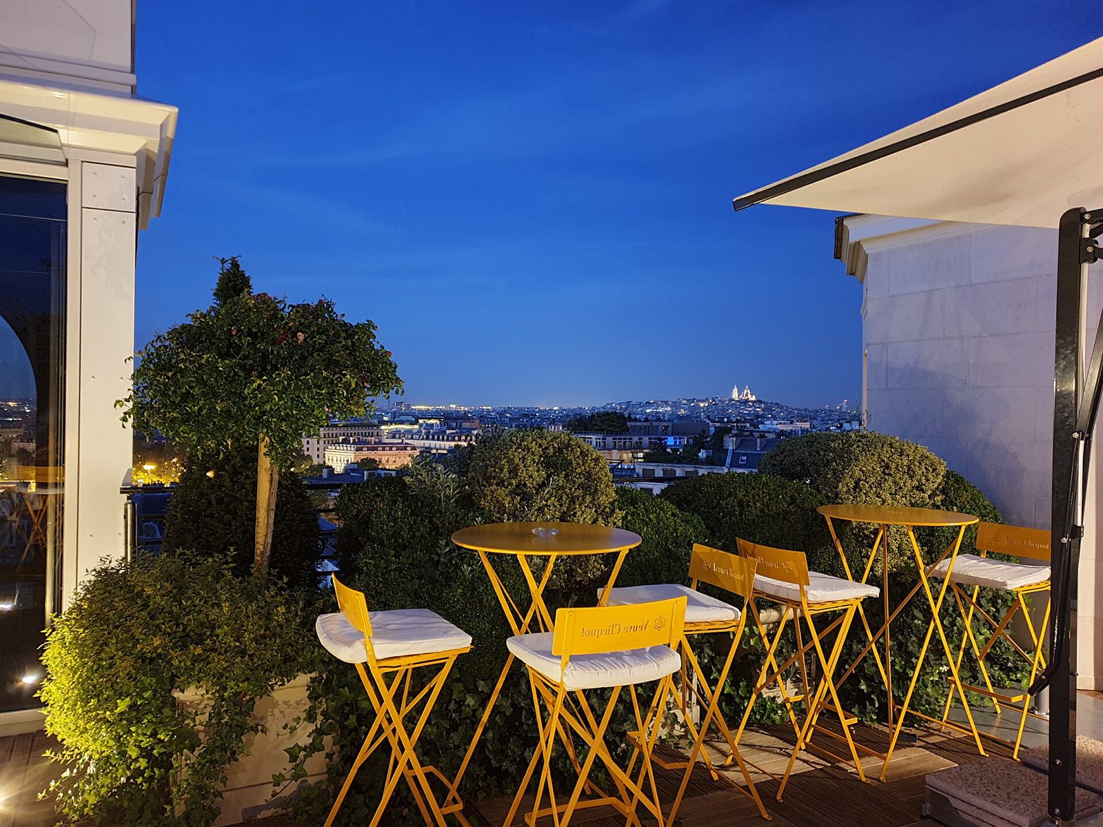 The terrace on the roof of the Hôtel Raphael at dusk, with yellow chairs and Paris beyond.