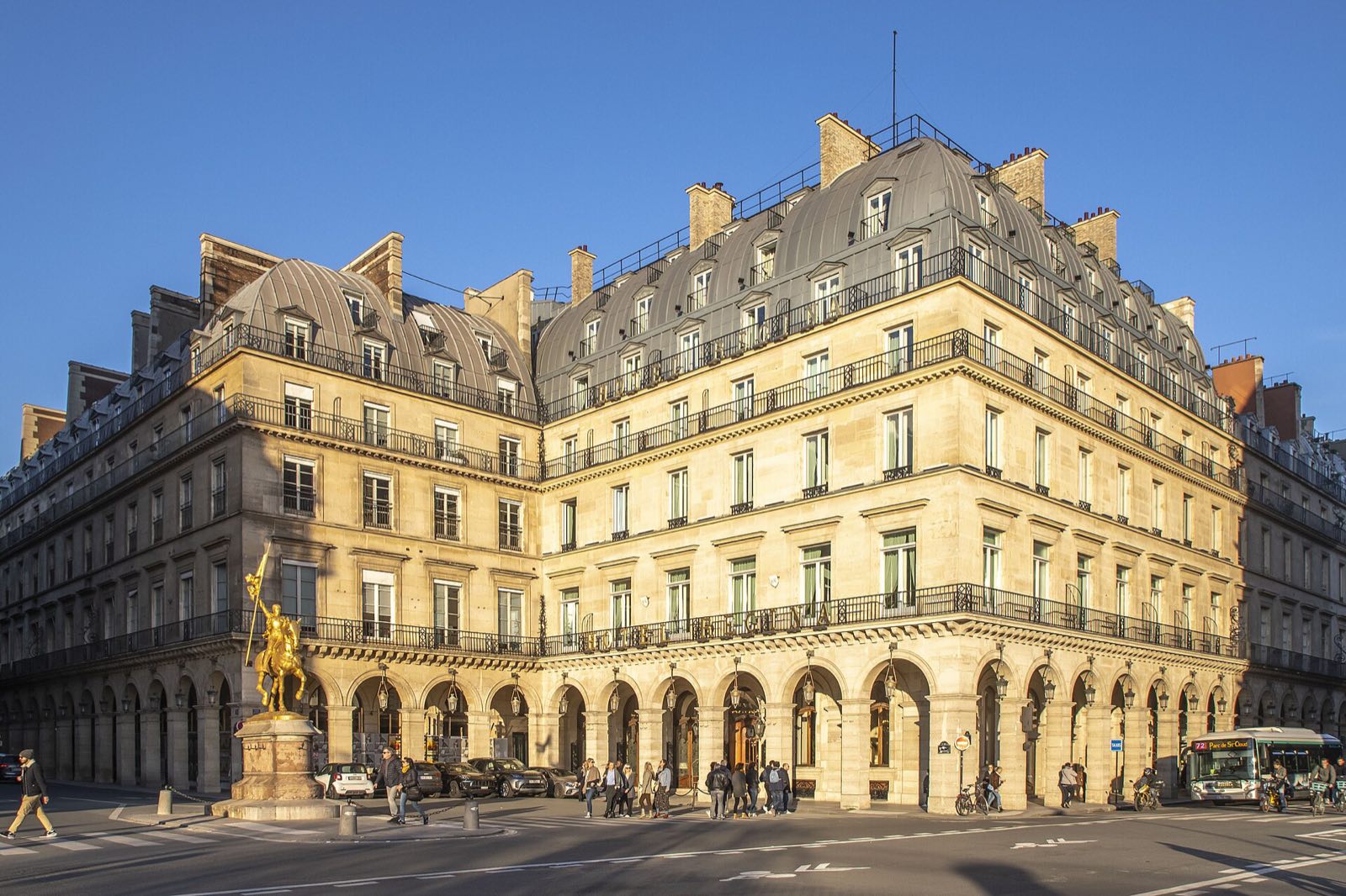 The Hôtel Regina Louvre on the Place des Pyramides in evening light, with the gilded statue of Joan of Arc in front.