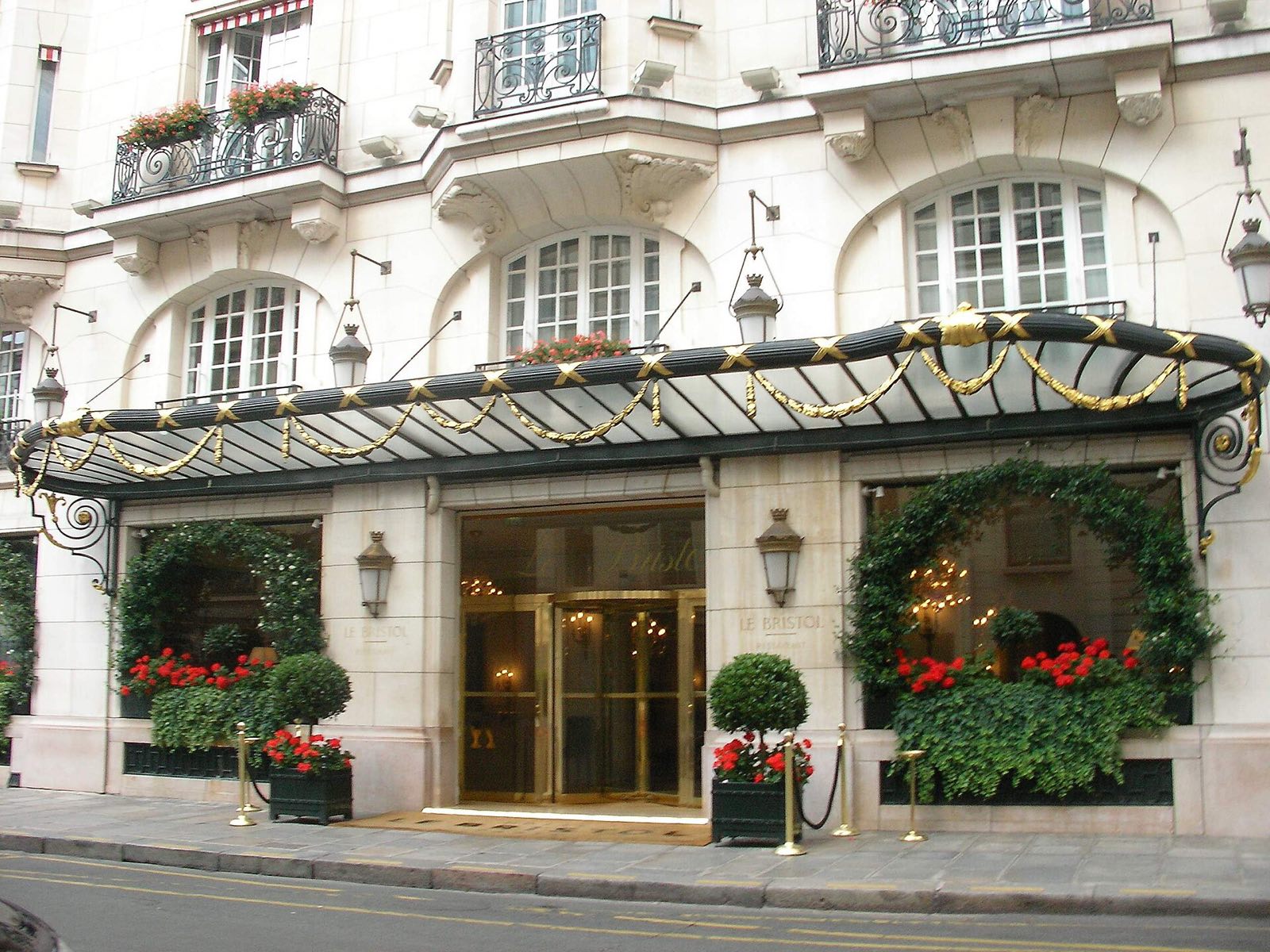 The entrance of Le Bristol on the rue du Faubourg Saint-Honoré, under a canopy of glass and iron hung with greenery.