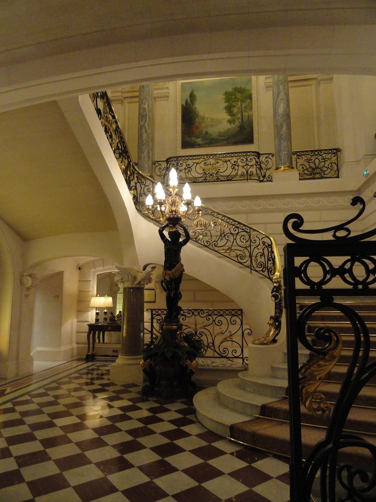 The main staircase of the Shangri-La Paris, with a wrought-iron balustrade and a chequered floor.