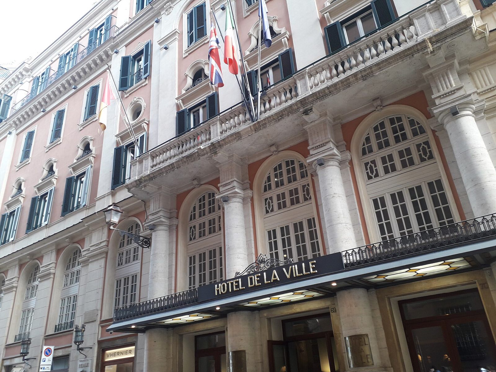 The white front of the Hotel de la Ville on Via Sistina, with its arched windows and flags.