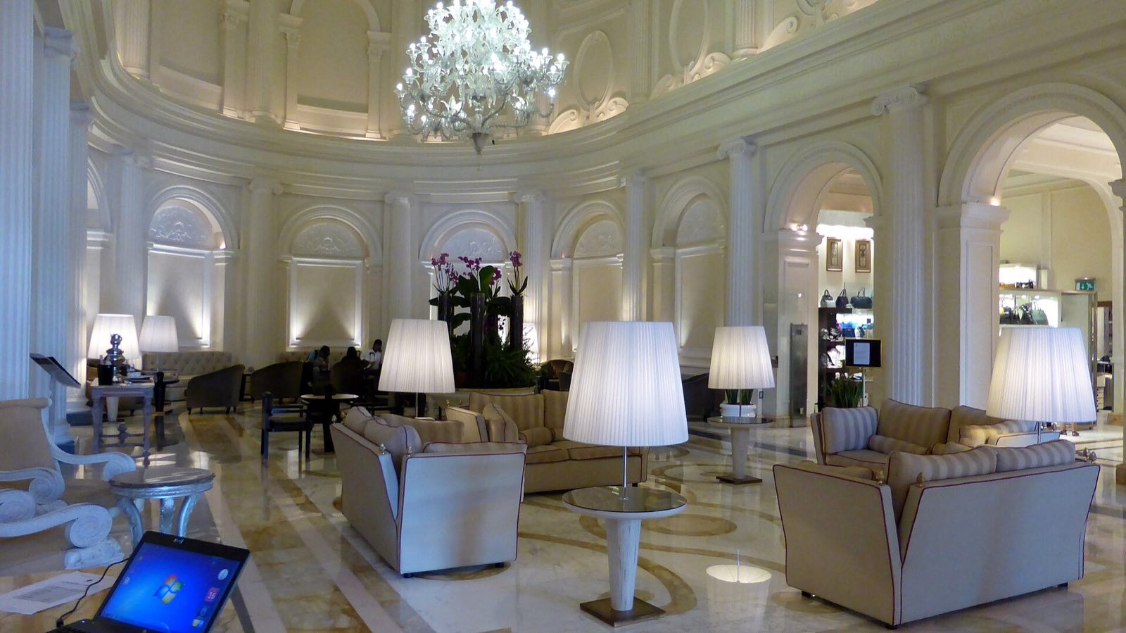 The white lobby of the hotel on Piazza della Repubblica, with sofas and a chandelier.