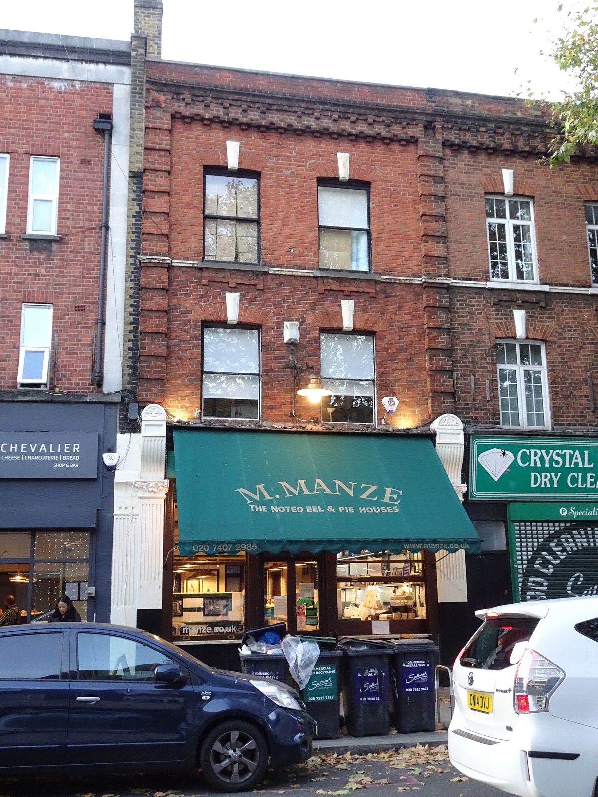 M.Manze on Tower Bridge Road, a shop with a green awning under a brick terrace.