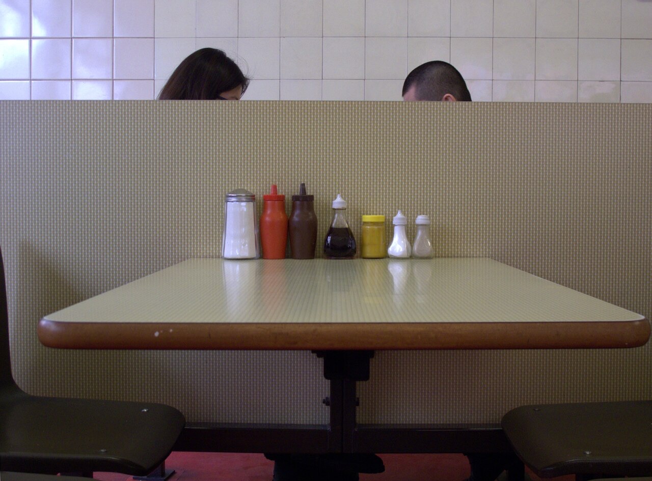 A Formica table and fixed seats inside the Regency Cafe, with sauce bottles lined up.
