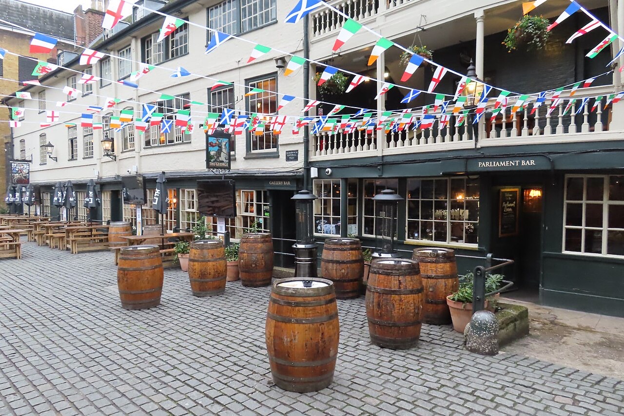 The yard of the George Inn in Southwark, with barrels for tables under two tiers of galleries.