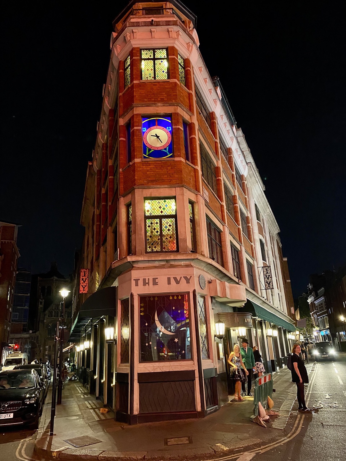 The Ivy lit at night, its corner windows glowing.