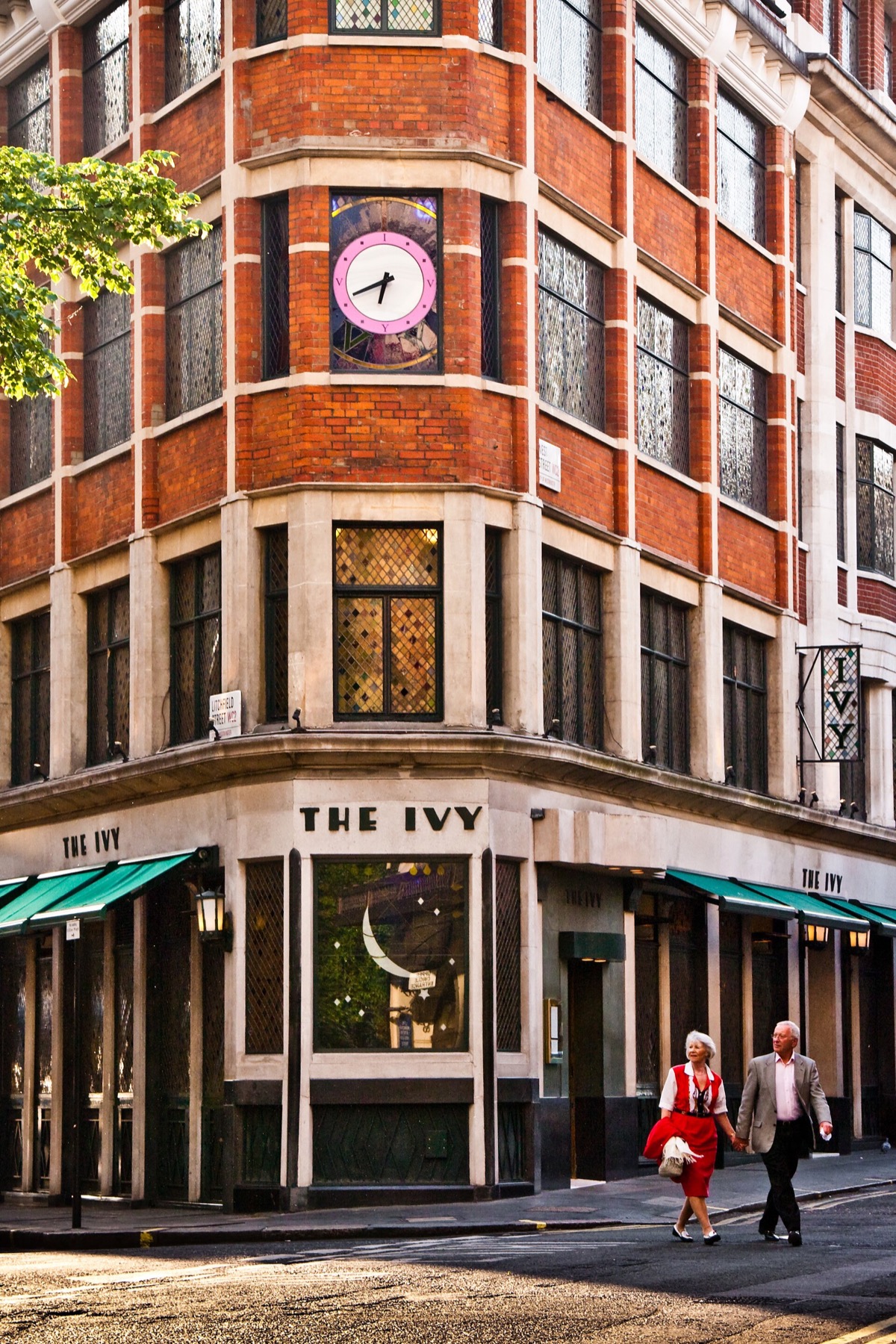 The corner entrance of The Ivy under its green awnings.