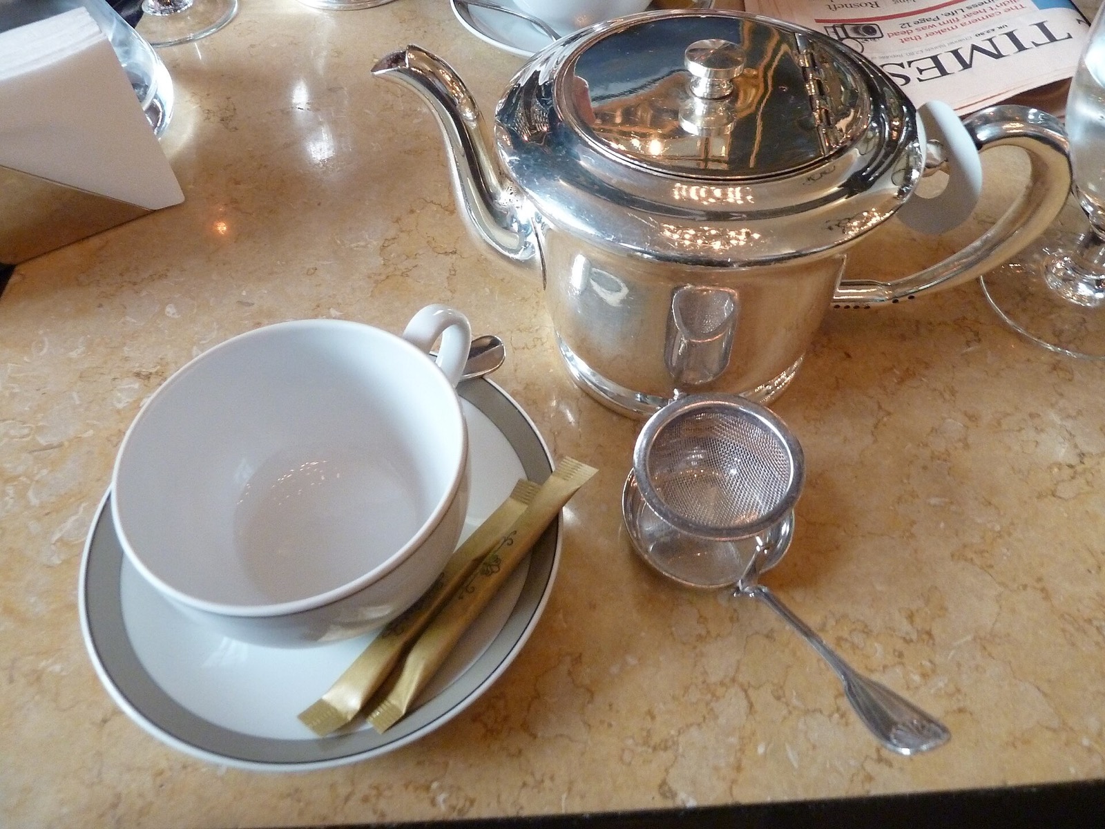 A silver teapot and a cup on a marble table at The Wolseley.