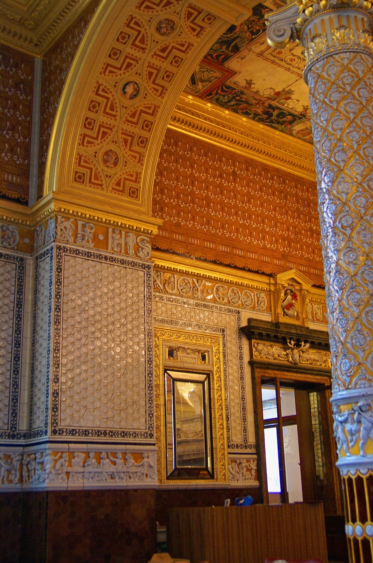 Columns and walls covered in cream and gold ceramic tiles in the refreshment rooms of the V&A.