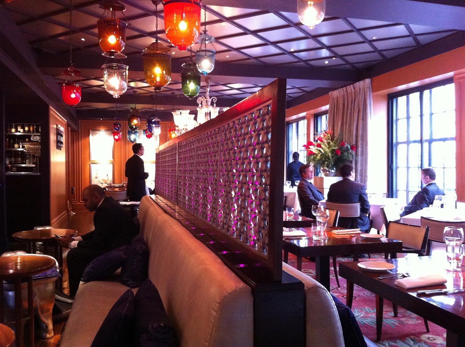 The dining room of Veeraswamy, with coloured glass lamps and a carved screen.