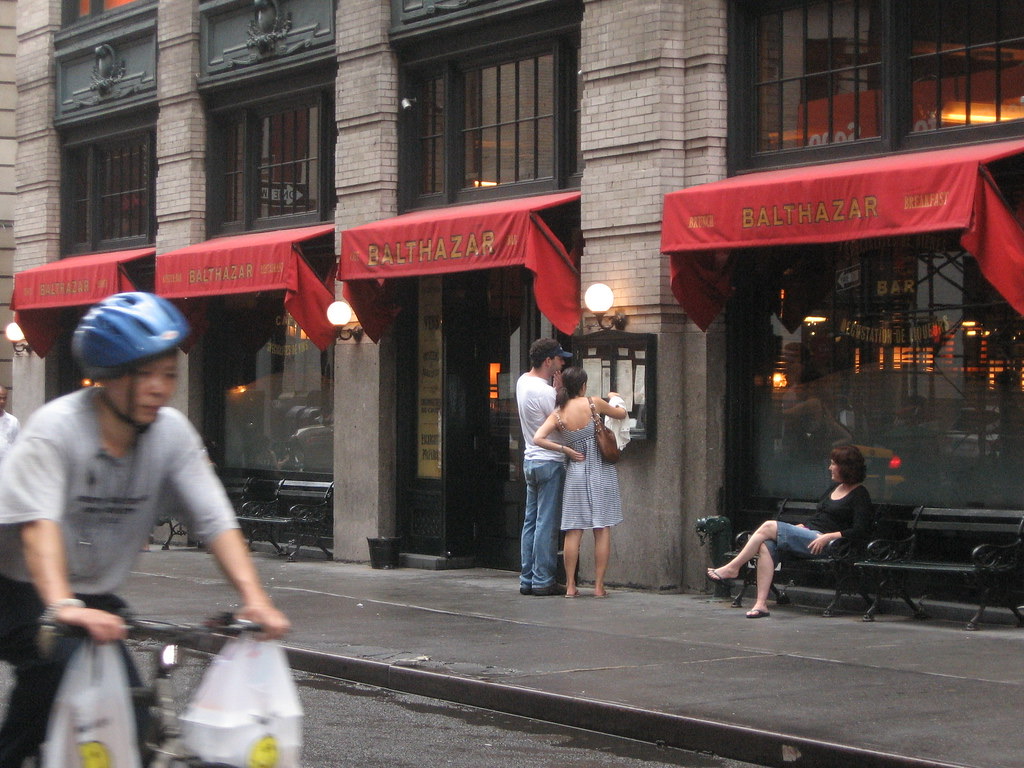 Balthazar seen from across Spring Street, with a cyclist passing.