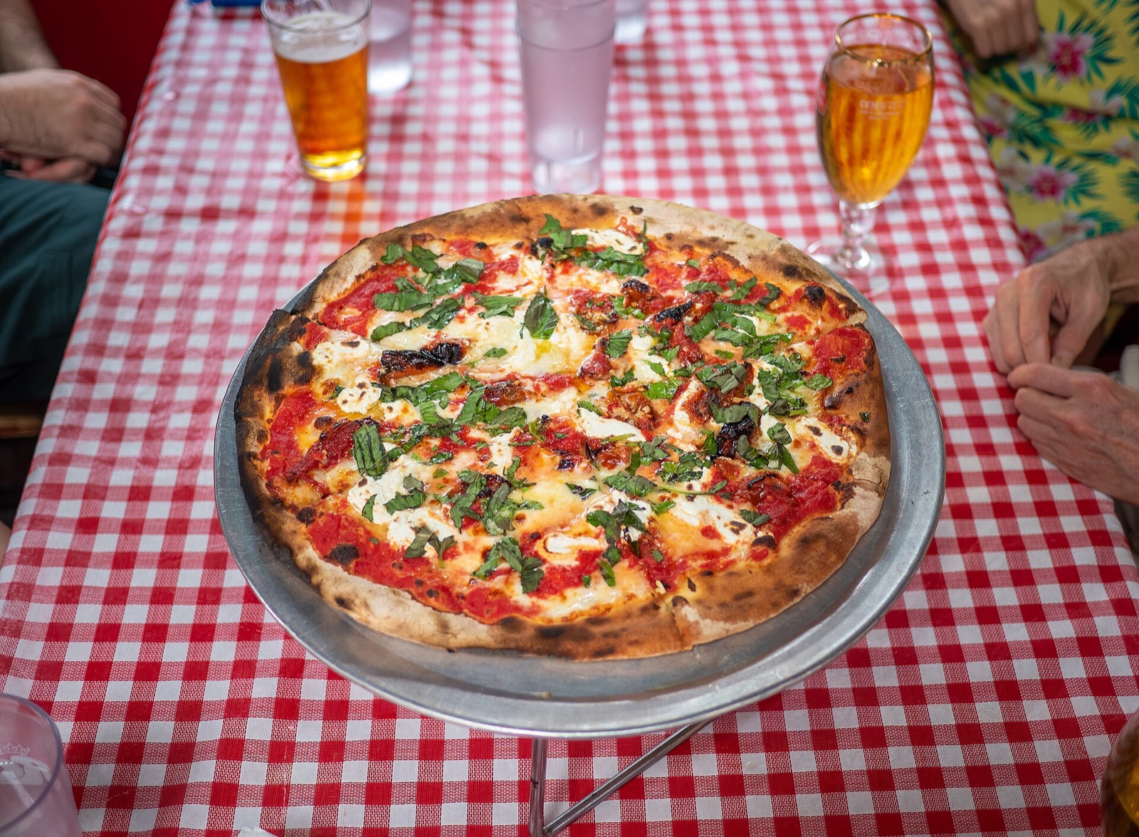 A pizza on a red checked tablecloth at John's of Bleecker Street.