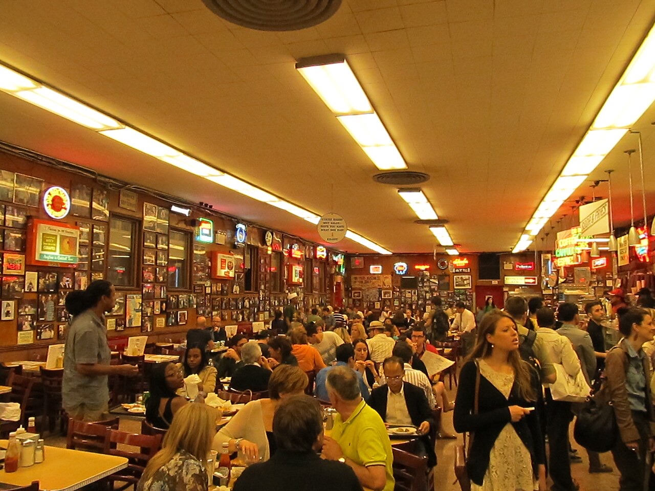 The dining room at Katz's Delicatessen, crowded under strip lights, with photographs along the walls.