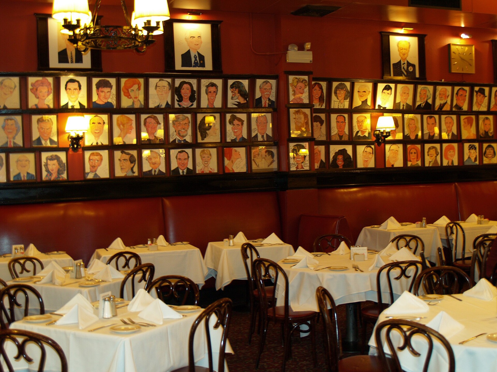 Tables laid for dinner at Sardi's under rows of caricatures of actors.