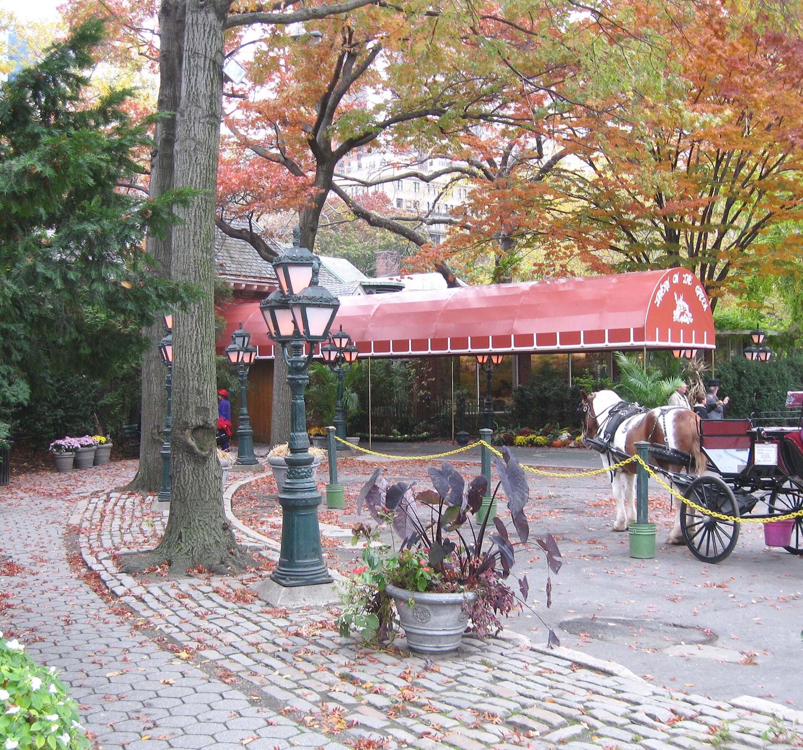 The entrance of Tavern on the Green in Central Park in autumn, under a red canopy.