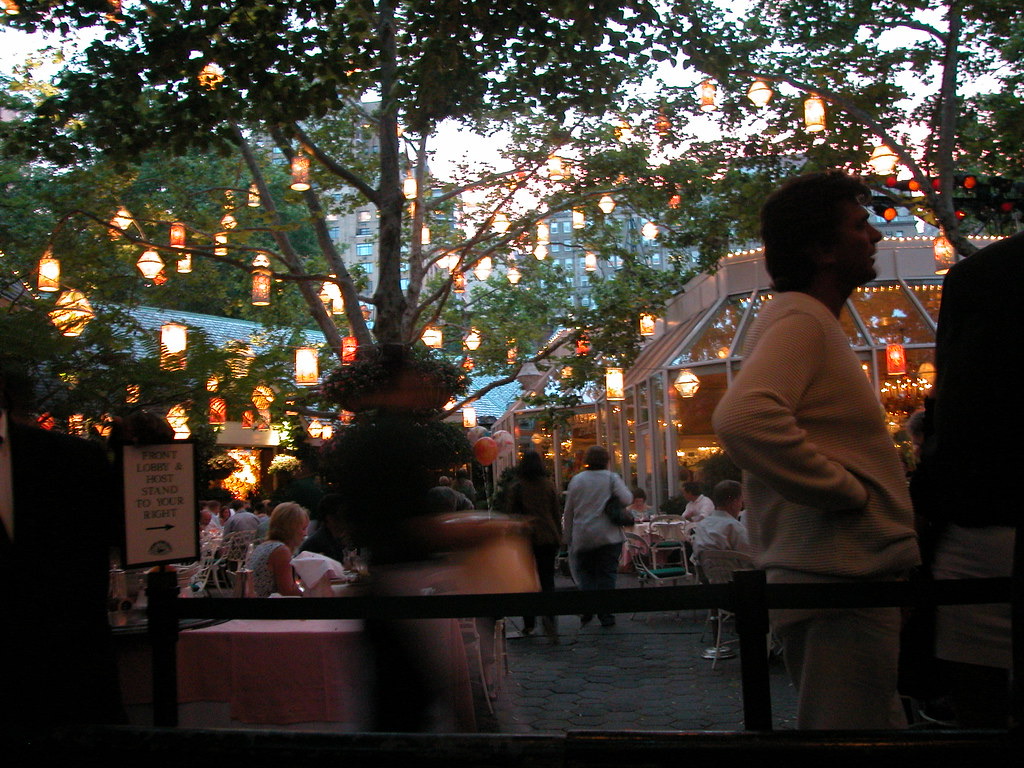 The courtyard of Tavern on the Green at dusk, with lanterns hung in the trees.