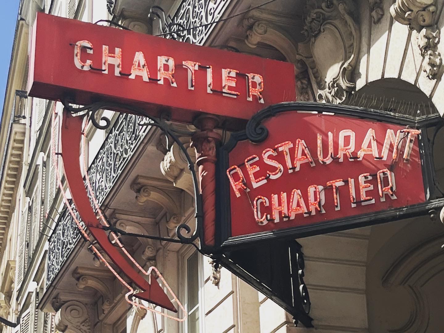 The red neon sign of the Restaurant Chartier over the entrance to its courtyard.