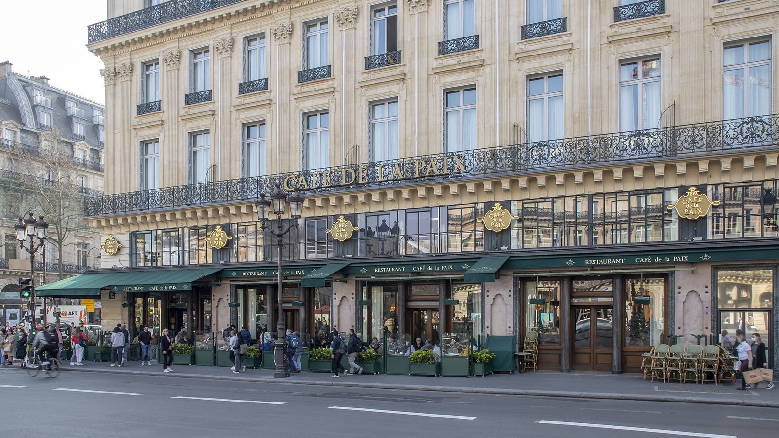The Café de la Paix at the corner of the Place de l'Opéra, green awnings along the pavement.