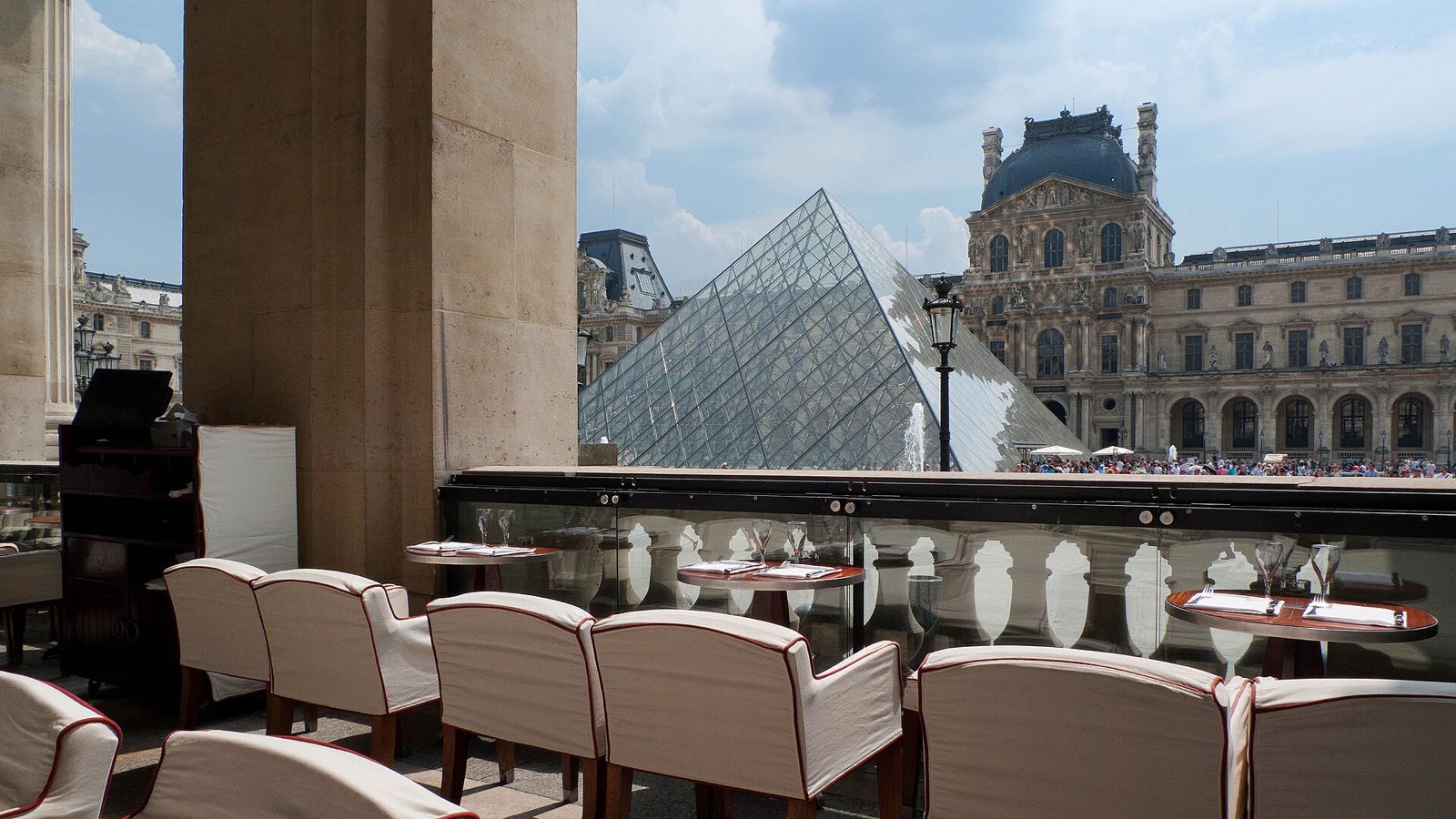 The terrace of the Café Marly under the arcades of the Louvre, with the glass pyramid beyond.