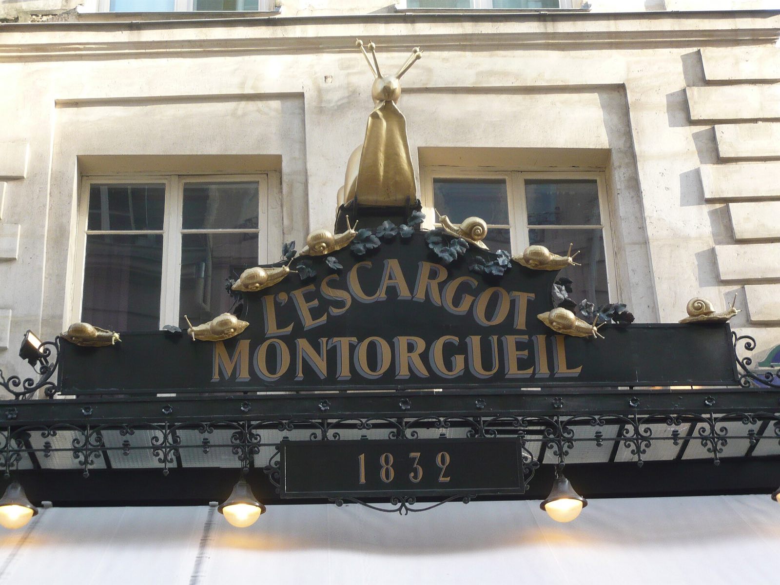 The black and gold sign of L'Escargot Montorgueil, with a gilded snail above it.