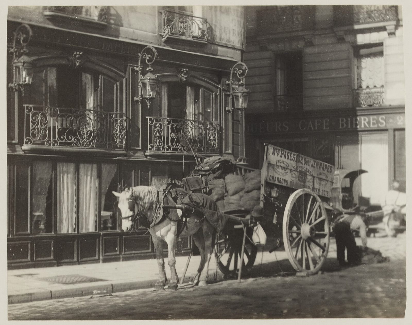 A coal merchant's cart stopped outside the restaurant Lapérouse, in a photograph of the late nineteenth century.