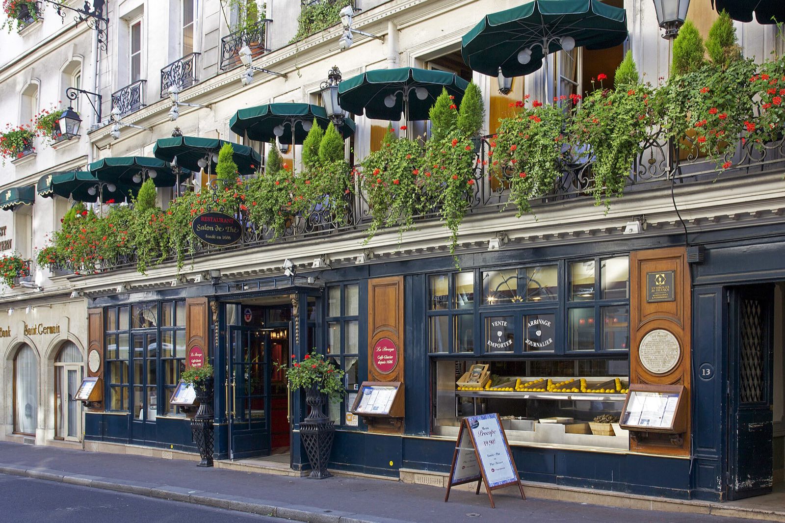 The dark blue front of Le Procope on the rue de l'Ancienne-Comédie, its balcony planted with flowers.