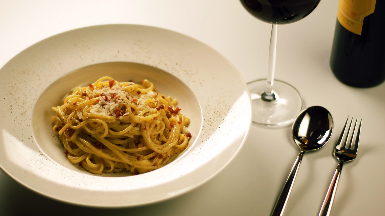 A plate of spaghetti alla carbonara with a glass of wine, the dish Roscioli is known for. Not photographed at the restaurant.