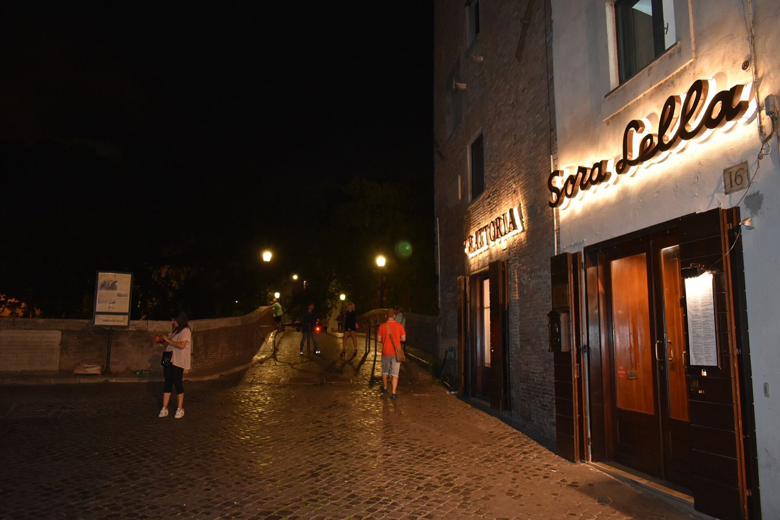 The lit sign of Sora Lella on the Tiber Island at night.