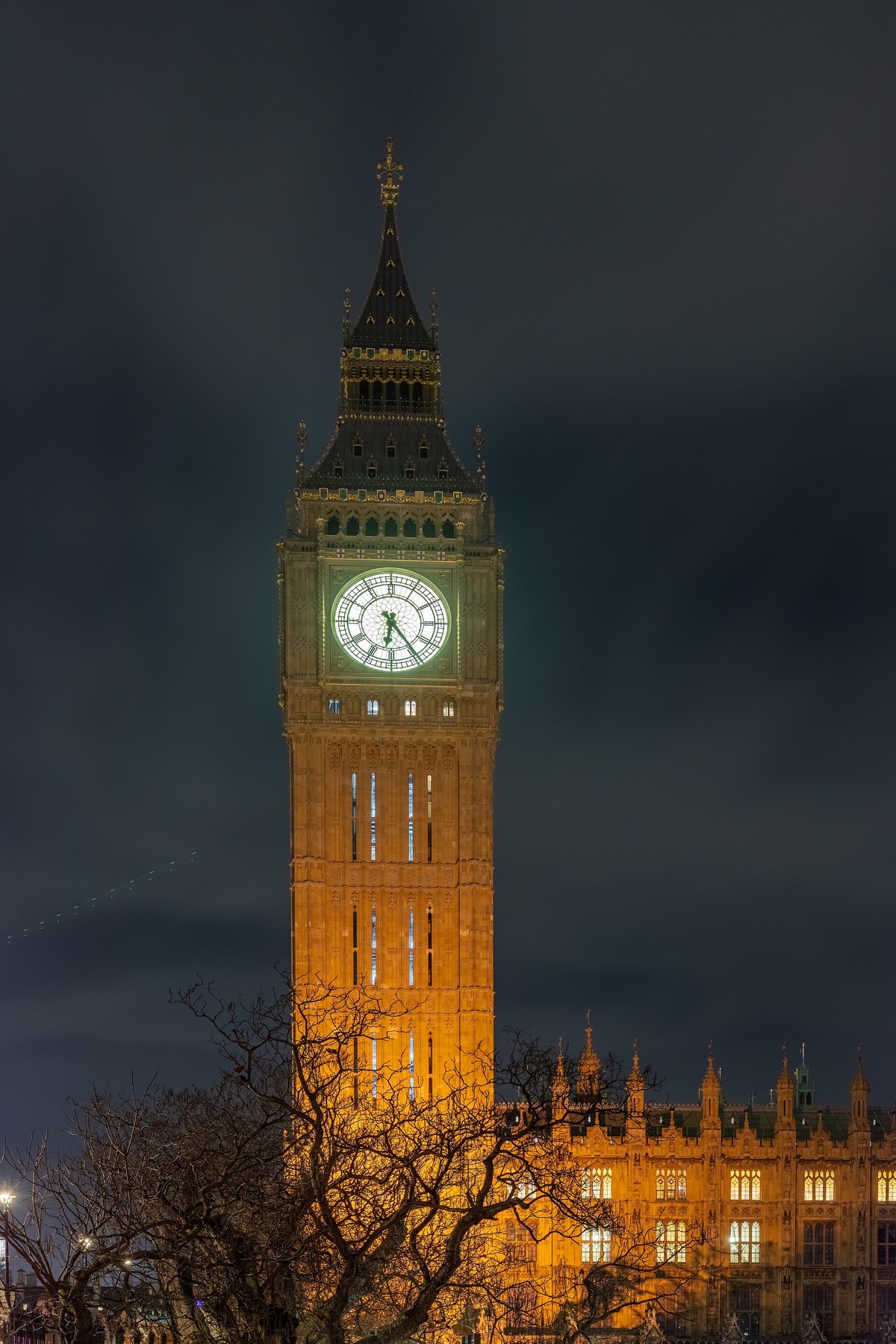 The clock tower of Big Ben lit at night, its four dials glowing.